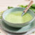 A bowl of green soup with a knife in it.