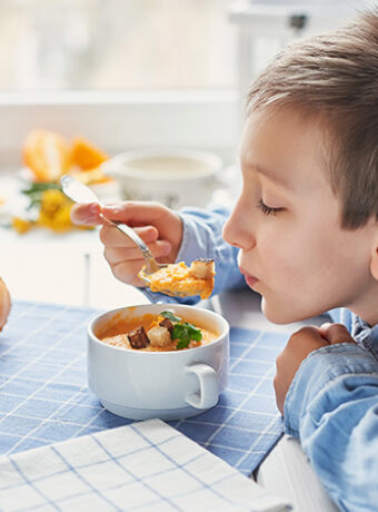 A young boy eating food from a bowl.