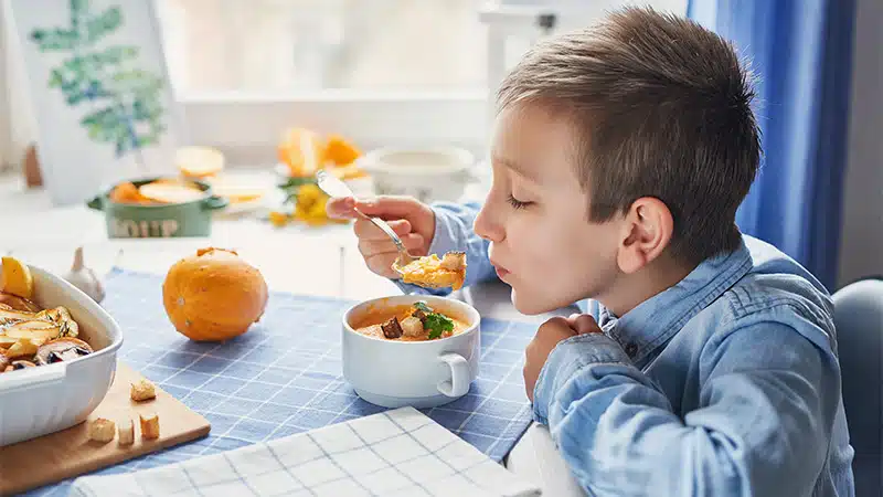 A young boy eating food from a bowl.
