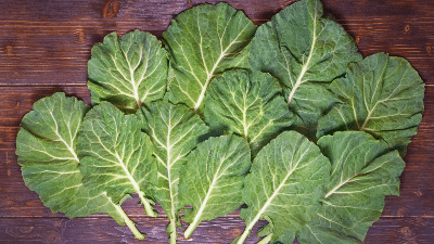 A group of green leaves on top of a wooden table.