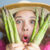 A woman holding asparagus up to her face.
