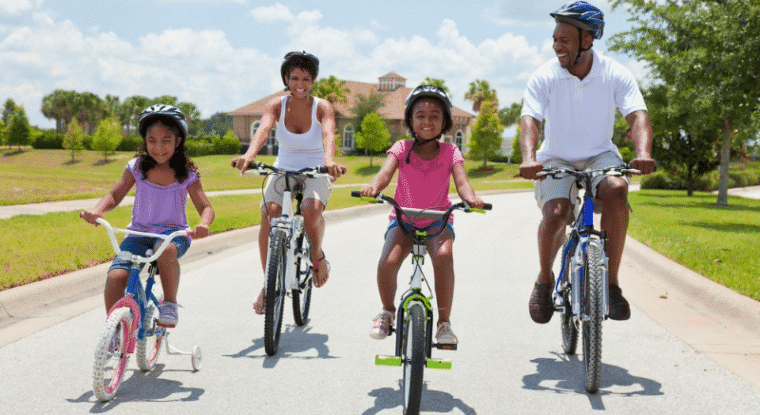 A mom, a dad, and their two daughters ride their bicycles together.