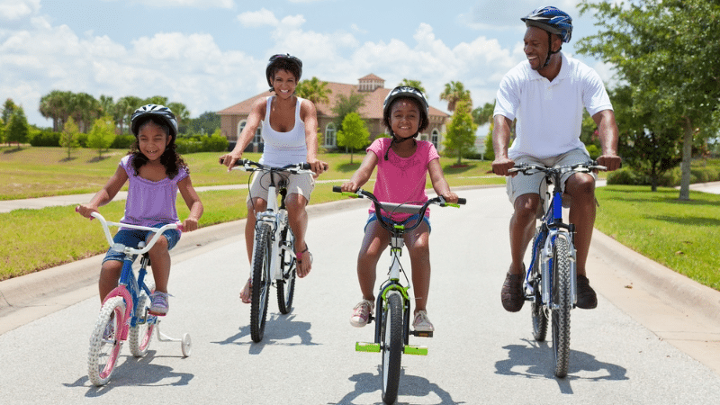 A mom, a dad, and their two daughters ride their bicycles together.