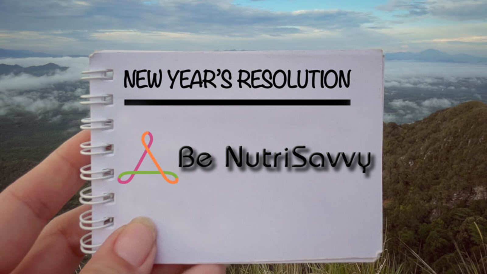 A person holding up a notebook with the words new year 's resolution written on it.