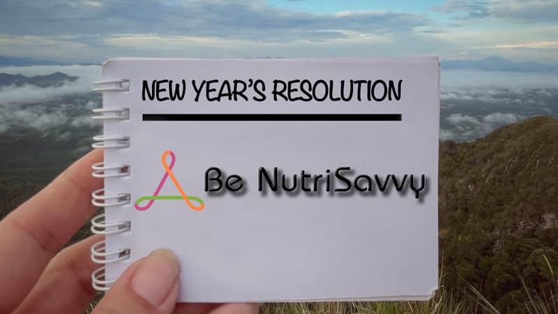 A person holding up a note with the words new year 's resolution written on it.
