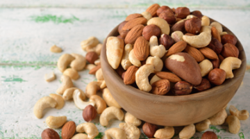 A bowl of nuts on the ground next to other nuts.