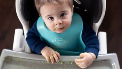 A baby in a car seat eating food.