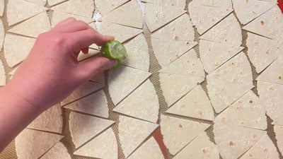 A person holding a piece of food on top of a floor.