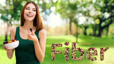 A woman holding a pen in her hand and the word fiber spelled out with nuts.