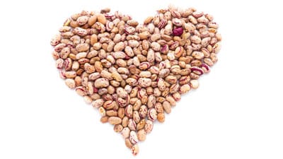 A heart made of beans on top of white background.