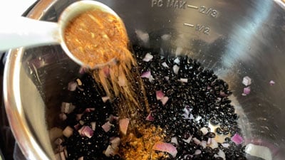 A bowl of black beans being cooked in sauce.