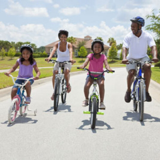A mom, a dad, and their two daughters ride their bicycles together.