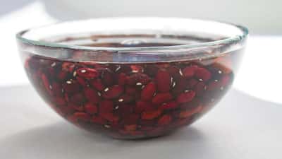A bowl of pomegranate seeds is sitting on the counter.