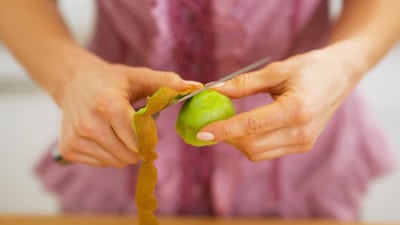 A person cutting an apple with scissors.