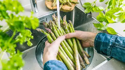 A person holding asparagus in a bowl