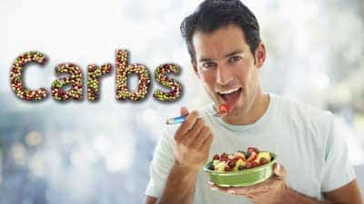 A man eating fruit in front of the word carbs.